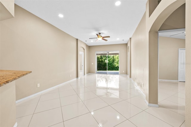 tiled empty room featuring ceiling fan