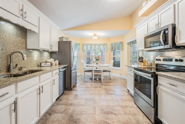 kitchen featuring sink, stainless steel appliances, vaulted ceiling, and tasteful backsplash