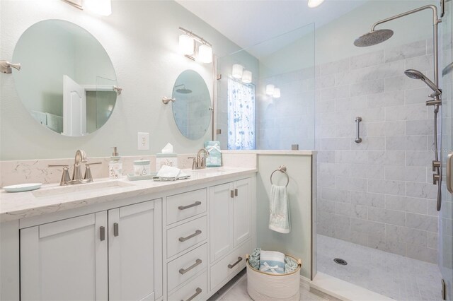 bathroom with dual bowl vanity and a shower with shower door