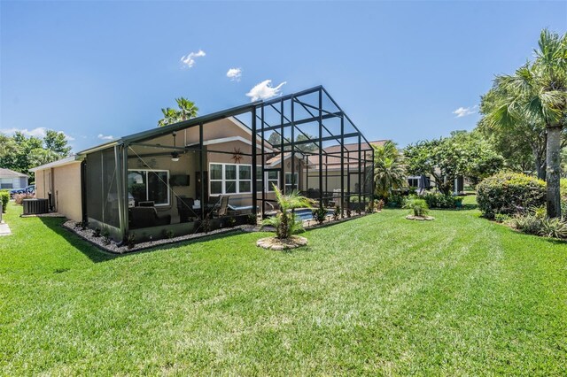 rear view of house with central AC, a lanai, and a lawn