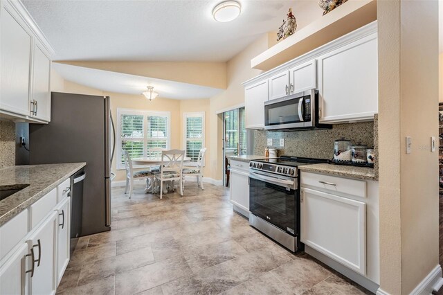 kitchen featuring white cabinets, tasteful backsplash, appliances with stainless steel finishes, and lofted ceiling