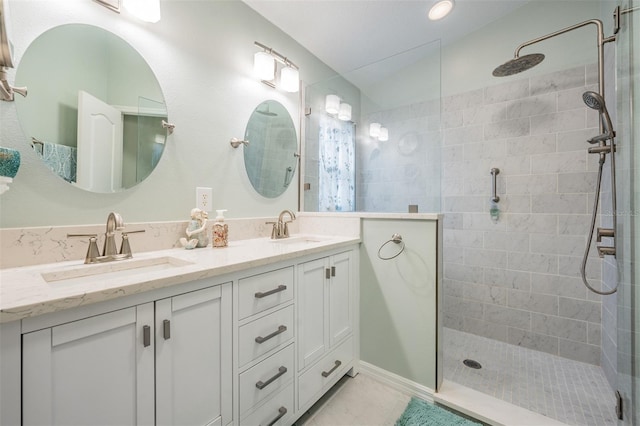 bathroom featuring tile patterned flooring, double sink vanity, and tiled shower