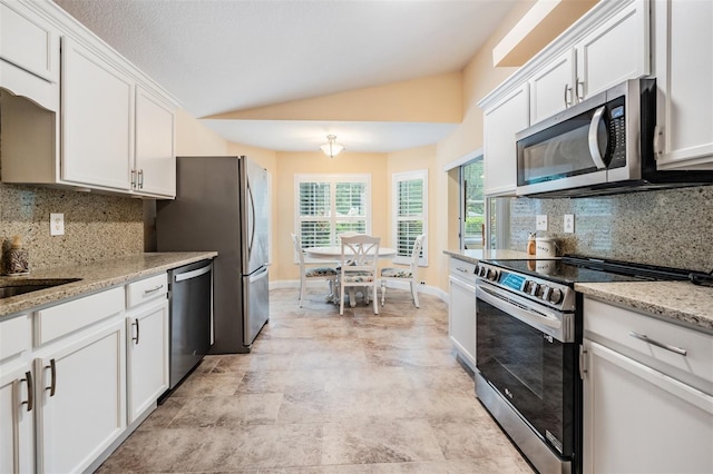 kitchen with appliances with stainless steel finishes, lofted ceiling, decorative backsplash, and light tile patterned floors