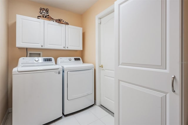 laundry room with washing machine and clothes dryer, cabinets, and light tile patterned floors