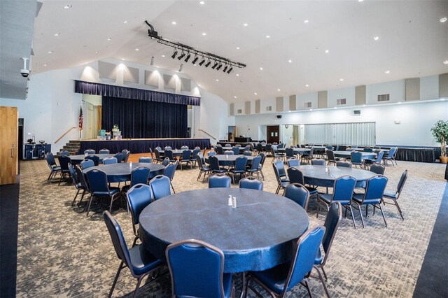 dining area with high vaulted ceiling and carpet flooring