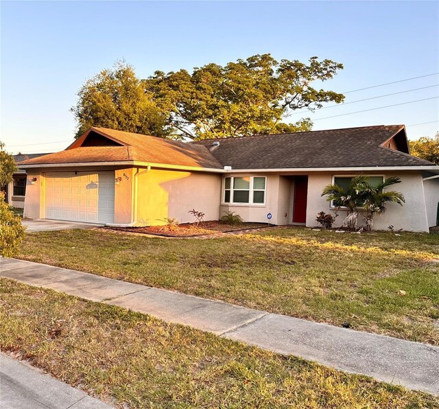 ranch-style house featuring a garage and a front lawn