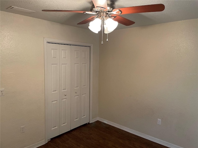 unfurnished bedroom featuring ceiling fan, dark hardwood / wood-style flooring, a closet, and a textured ceiling