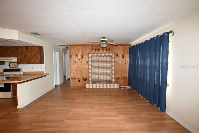 unfurnished dining area featuring wood walls, ceiling fan, and light hardwood / wood-style floors