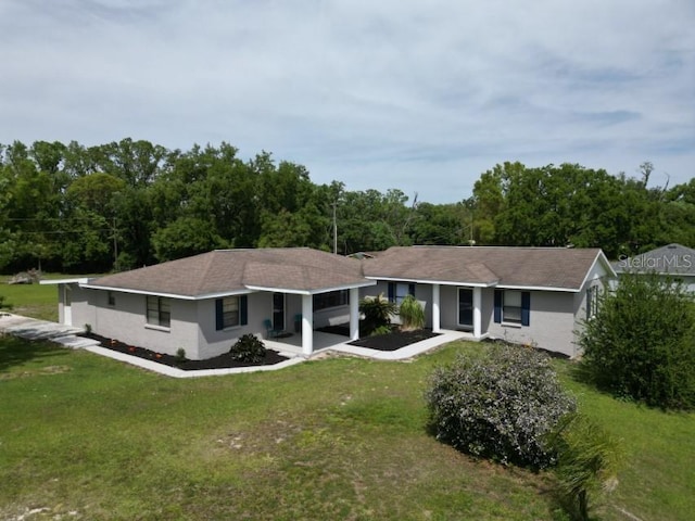 view of front of home with a carport, stucco siding, a view of trees, and a front lawn