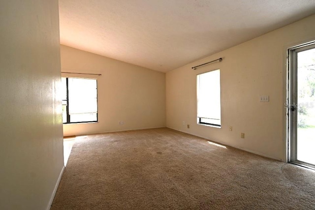carpeted spare room featuring a wealth of natural light and vaulted ceiling