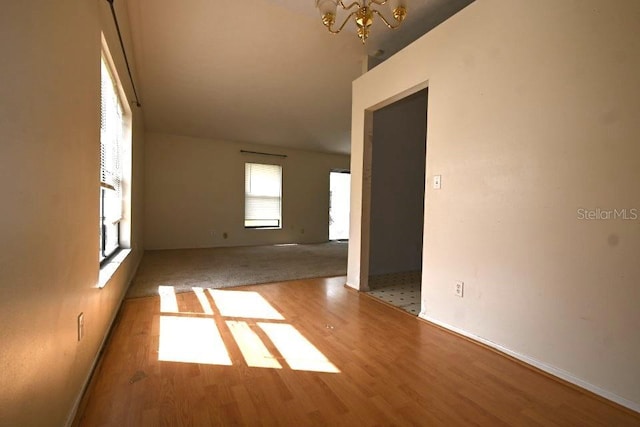 spare room featuring an inviting chandelier and wood finished floors