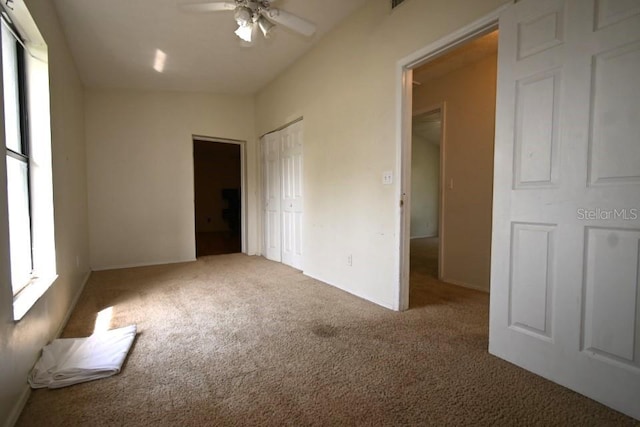 unfurnished bedroom with a closet, multiple windows, ceiling fan, and carpet floors