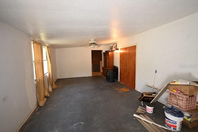 unfurnished living room with a textured ceiling, unfinished concrete flooring, and ceiling fan