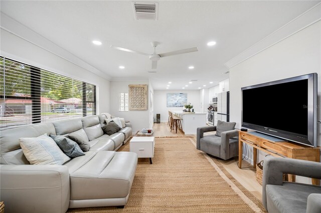 living room with light hardwood / wood-style flooring, ceiling fan, and crown molding