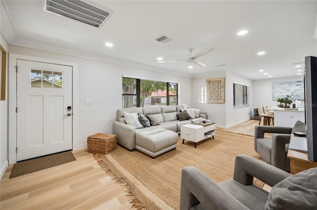 living room featuring light hardwood / wood-style floors, ceiling fan, and crown molding