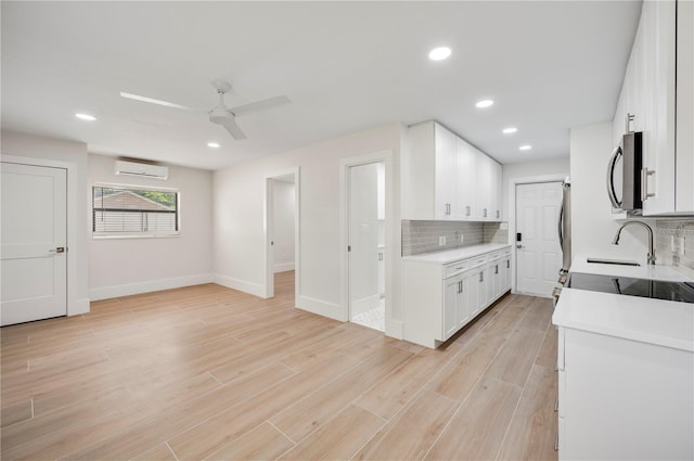 kitchen featuring white cabinetry, ceiling fan, a wall mounted air conditioner, tasteful backsplash, and a barn door