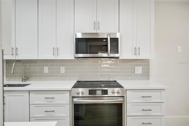 kitchen featuring light stone countertops, tasteful backsplash, stainless steel appliances, sink, and white cabinetry