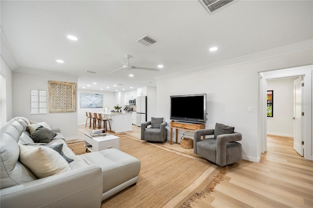 living room with ceiling fan, light hardwood / wood-style flooring, and crown molding