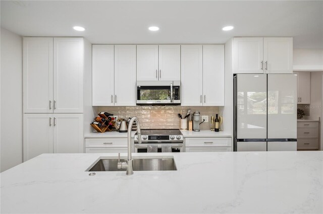 kitchen with white cabinetry, light stone counters, sink, and appliances with stainless steel finishes