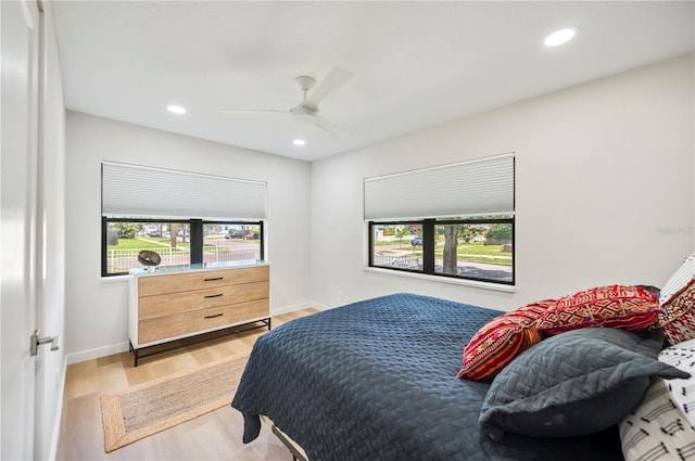 bedroom featuring ceiling fan, light hardwood / wood-style floors, and multiple windows