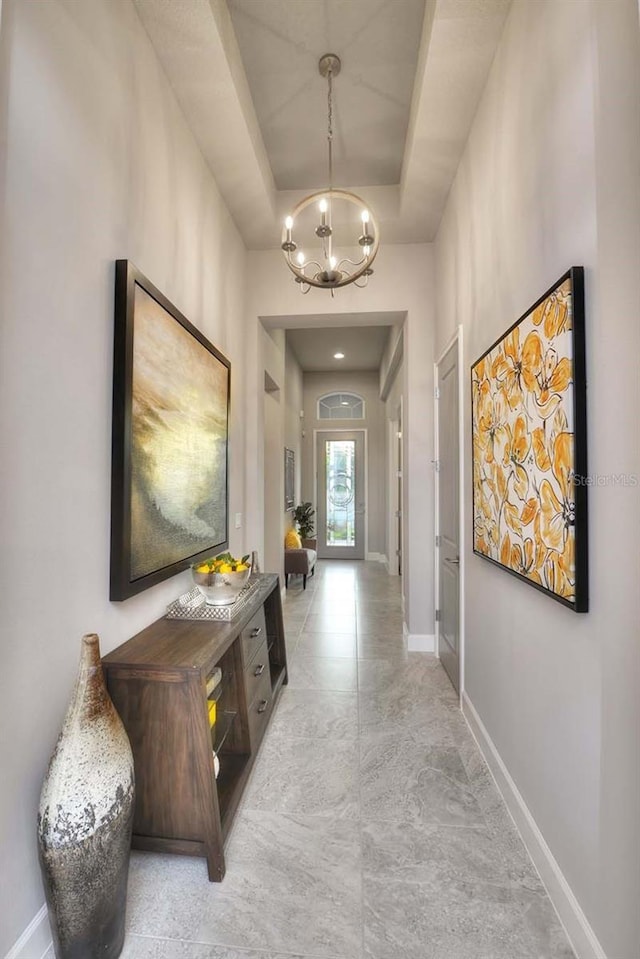 corridor featuring a notable chandelier and a tray ceiling