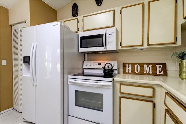 kitchen featuring light tile patterned floors, white appliances, and cream cabinets