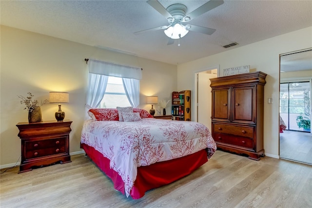 bedroom with ceiling fan, light hardwood / wood-style floors, and a textured ceiling