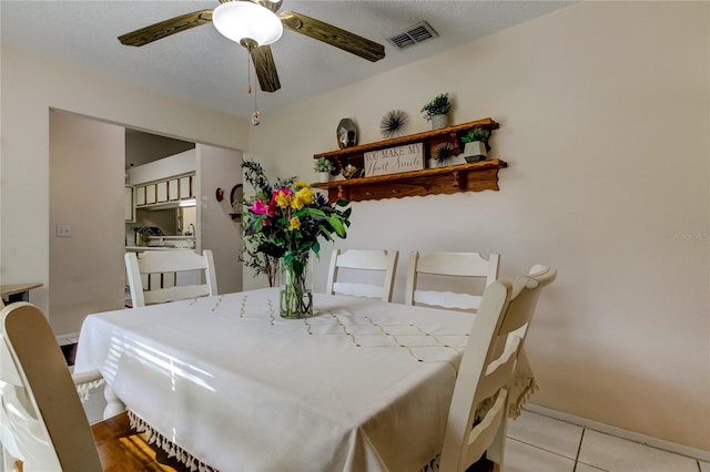 dining space featuring ceiling fan, light tile patterned flooring, and a textured ceiling