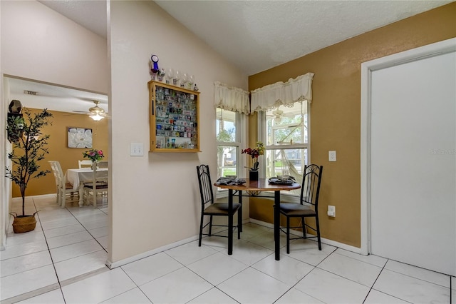 tiled dining space with ceiling fan and lofted ceiling