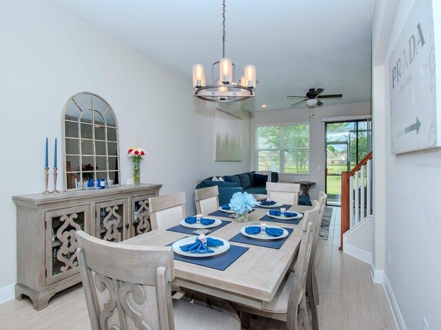 dining room featuring light wood-type flooring and ceiling fan with notable chandelier