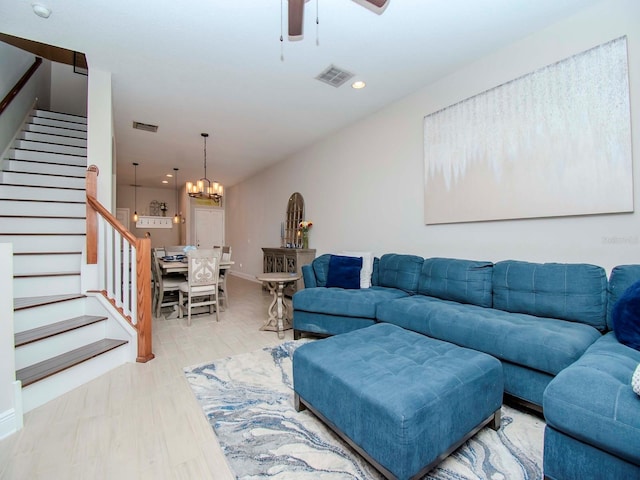 living room with ceiling fan with notable chandelier and light hardwood / wood-style flooring