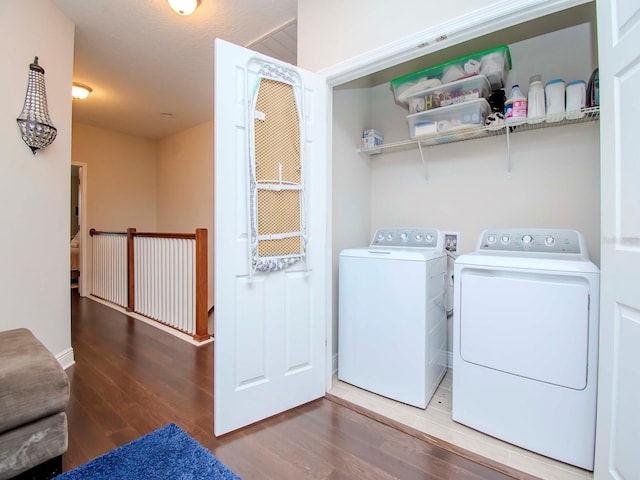 clothes washing area featuring wood-type flooring and washer and clothes dryer