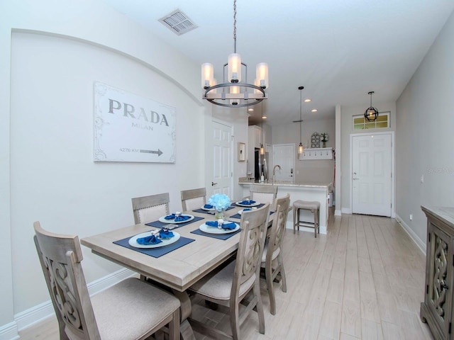 dining space featuring an inviting chandelier, sink, and light hardwood / wood-style floors