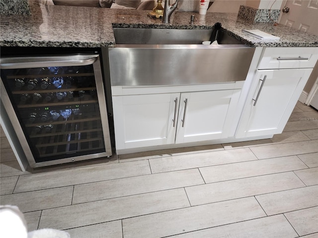 details featuring white cabinets, dark stone countertops, and wine cooler