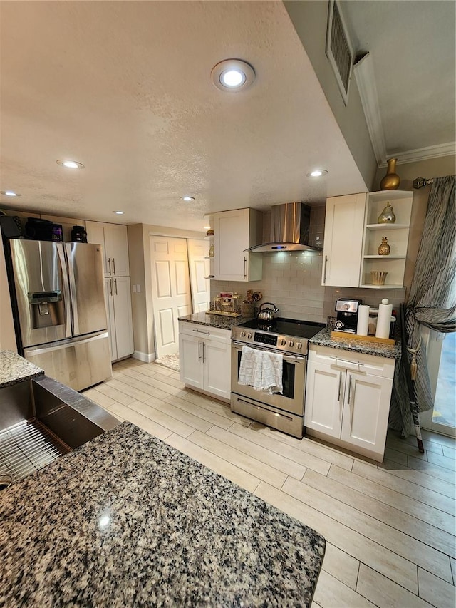 kitchen featuring light hardwood / wood-style floors, tasteful backsplash, stainless steel appliances, and wall chimney exhaust hood