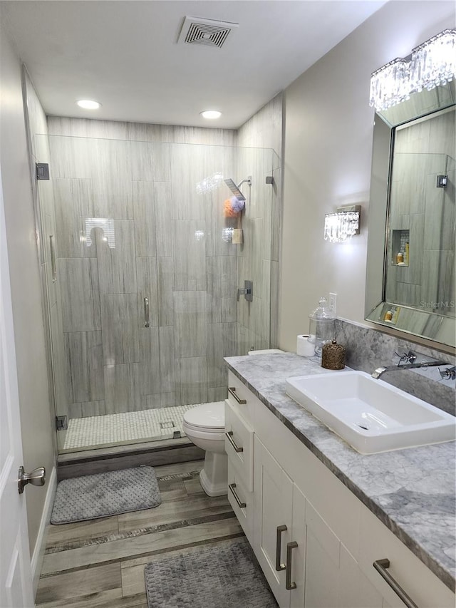 bathroom featuring vanity, a shower with door, hardwood / wood-style flooring, and toilet