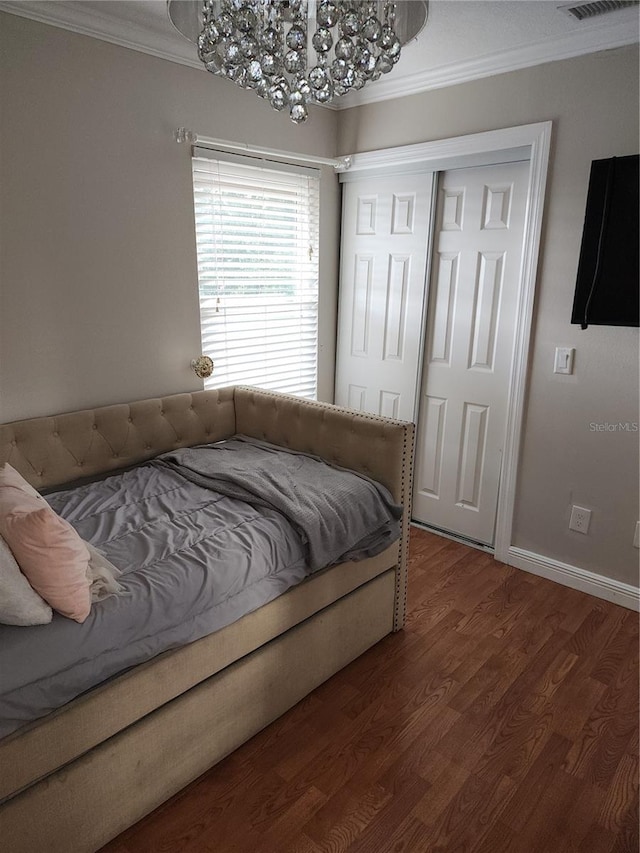 bedroom with crown molding, hardwood / wood-style flooring, a notable chandelier, and a closet