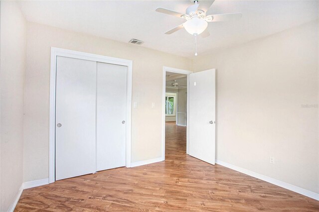 unfurnished bedroom featuring light hardwood / wood-style floors, ceiling fan, and a closet