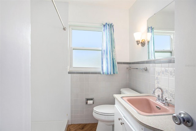 bathroom with tile walls, a shower, vanity, and toilet