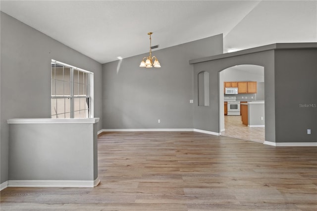 unfurnished room with light hardwood / wood-style flooring, a notable chandelier, and high vaulted ceiling