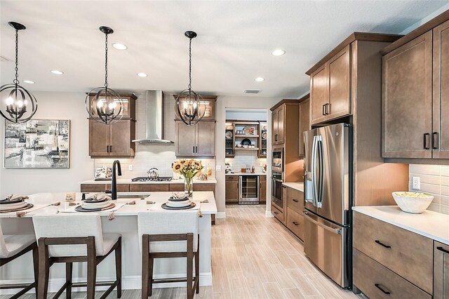 kitchen featuring stainless steel appliances, decorative light fixtures, backsplash, and wall chimney range hood