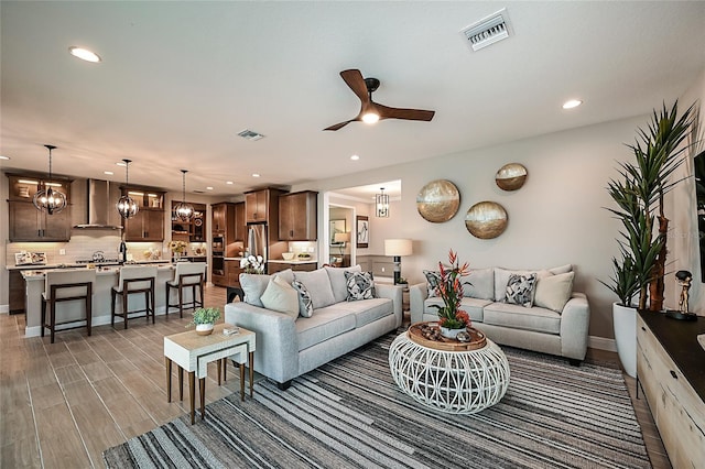 living room featuring ceiling fan with notable chandelier and hardwood / wood-style flooring