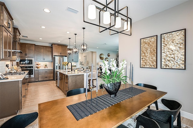 dining room featuring an inviting chandelier, sink, and light hardwood / wood-style flooring