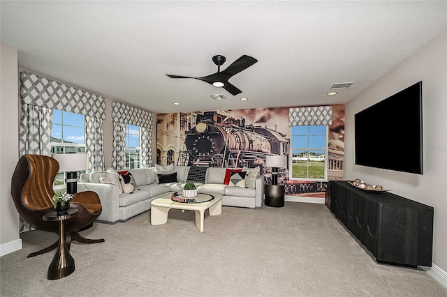 living room featuring ceiling fan, light carpet, and a textured ceiling