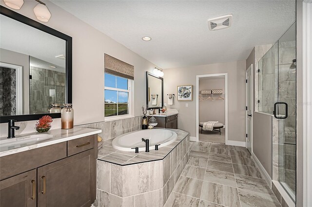 bathroom with independent shower and bath, tile patterned floors, vanity, and a textured ceiling