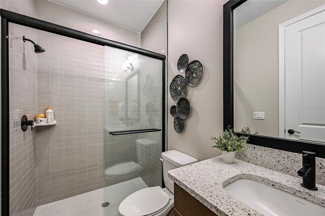 bathroom featuring vanity, toilet, and a shower with door