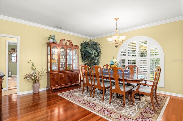 dining area featuring dark hardwood / wood-style flooring, ornamental molding, and a chandelier