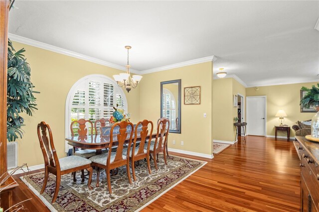 dining room with wood-type flooring, crown molding, and a chandelier