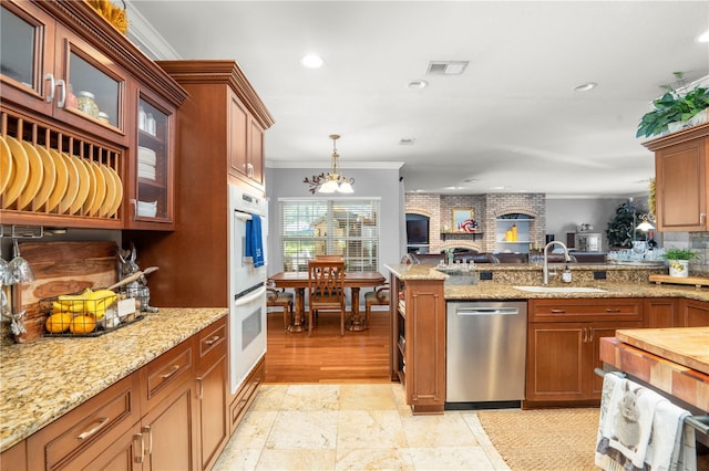 kitchen featuring sink, stainless steel dishwasher, a notable chandelier, pendant lighting, and ornamental molding