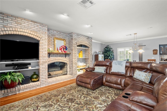 living room featuring ornamental molding, brick wall, wood-type flooring, an inviting chandelier, and a fireplace